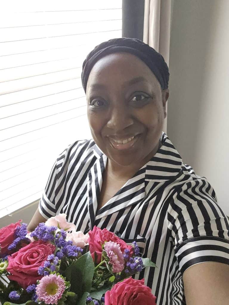 Image of Clarissa smiling while holding onto a bouquet of flowers she received following her surgery.